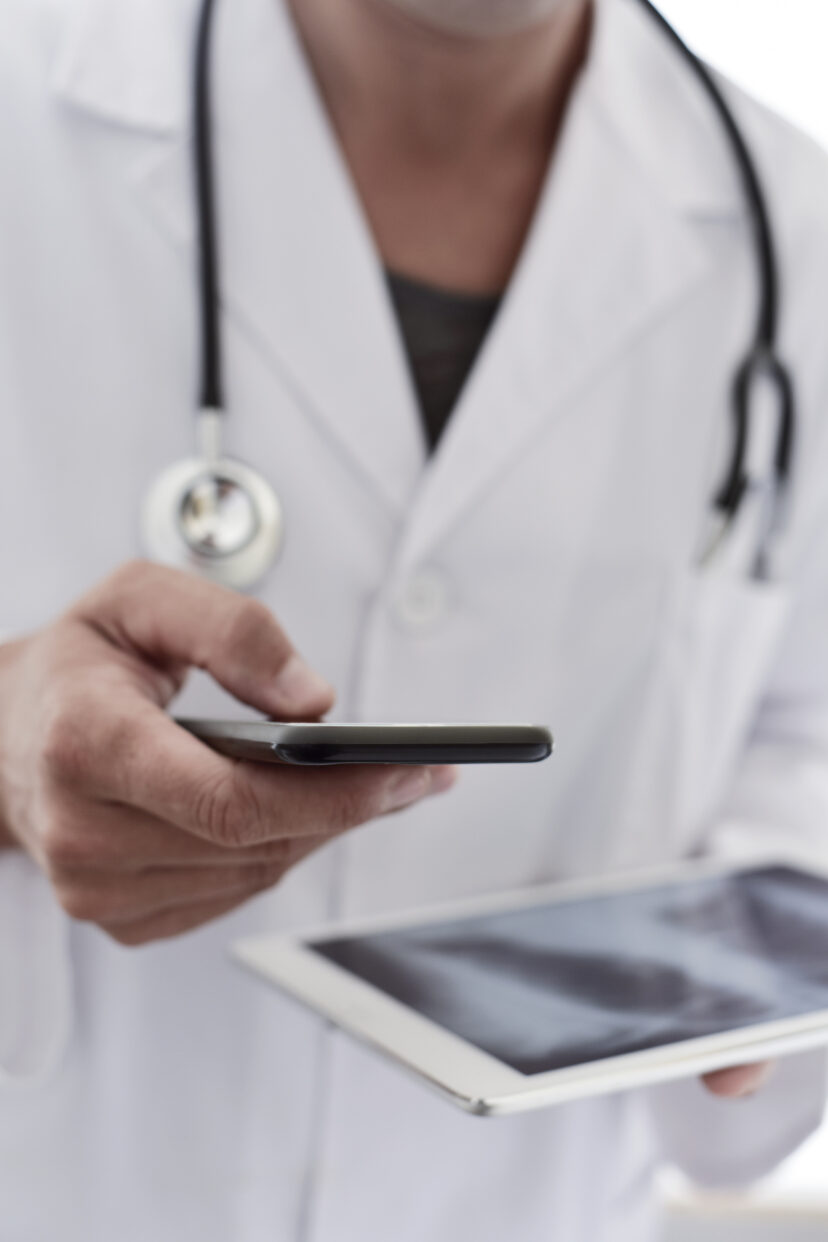 Médecin équipé d'un smartphone et d'une tablette