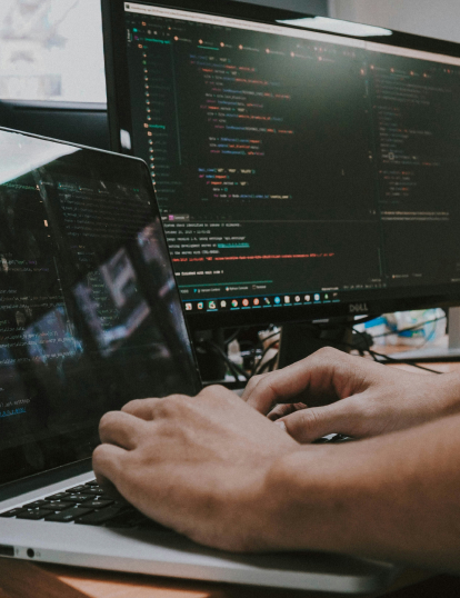Mains en train de taper sur un clavier d'ordinateur. A l'écran des lignes de code